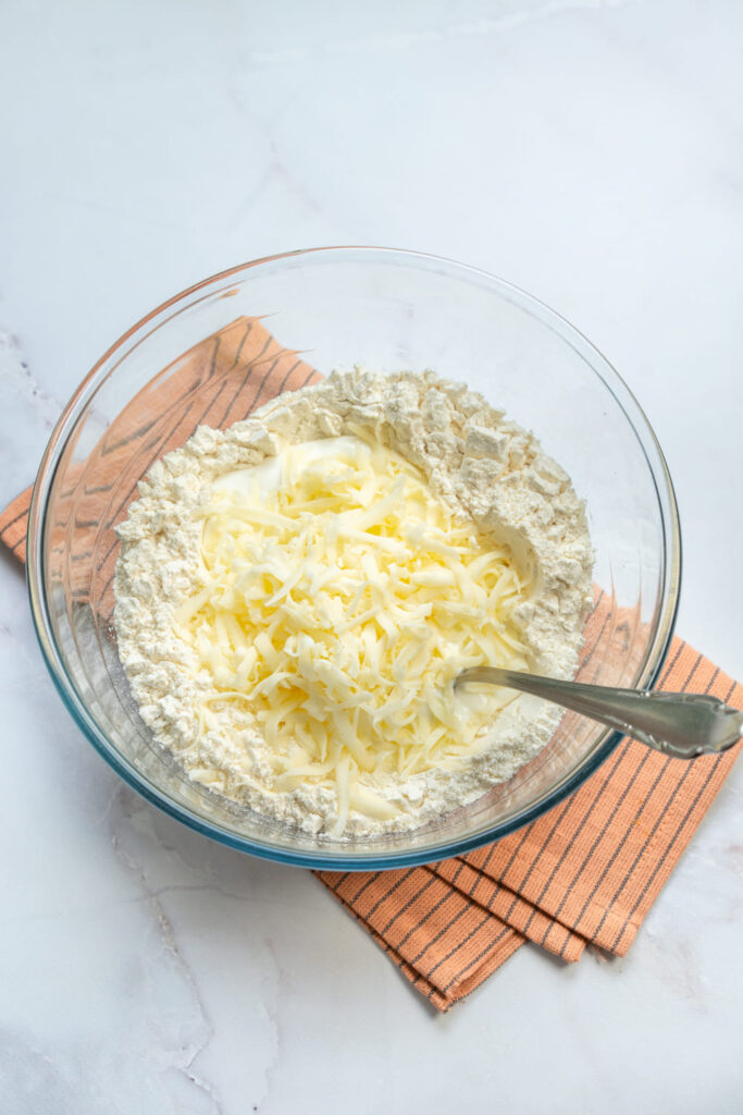 Flour mixed with shredded mozzarella and Greek yogurt in a glass bowl