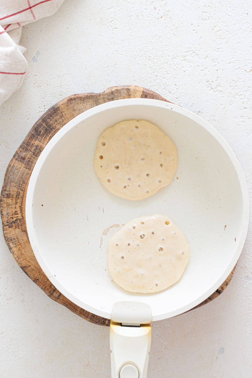Banana pancake batter forming small circles in a non-stick pan