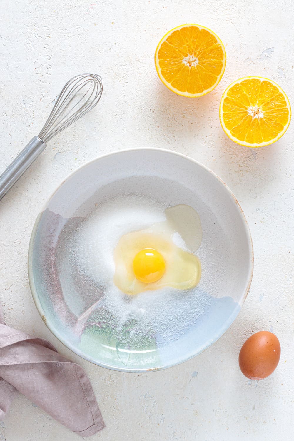 Egg and sugar in bowl with whisk for almond orange cake