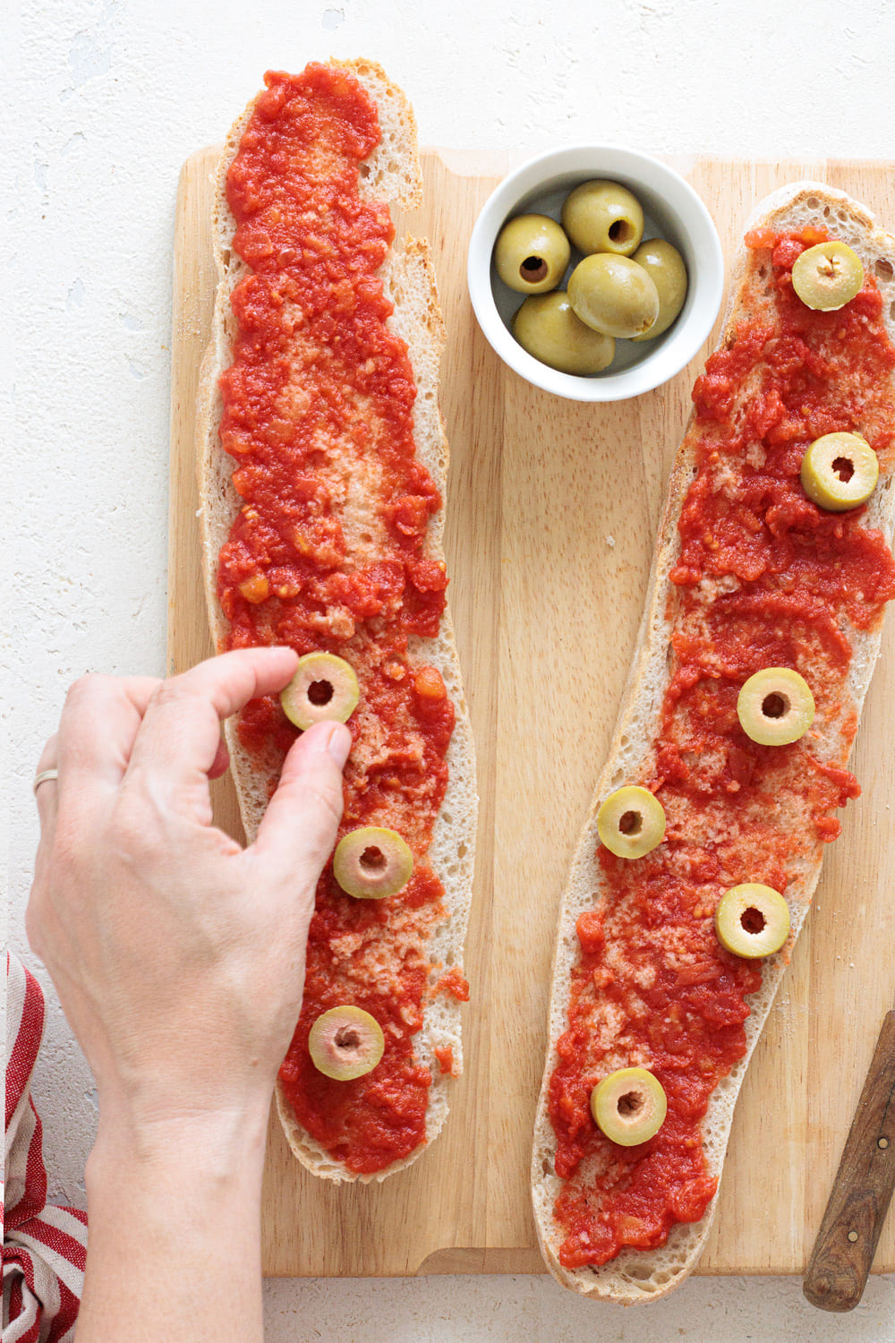 Green olives placed over the tomato base on the baguette slices