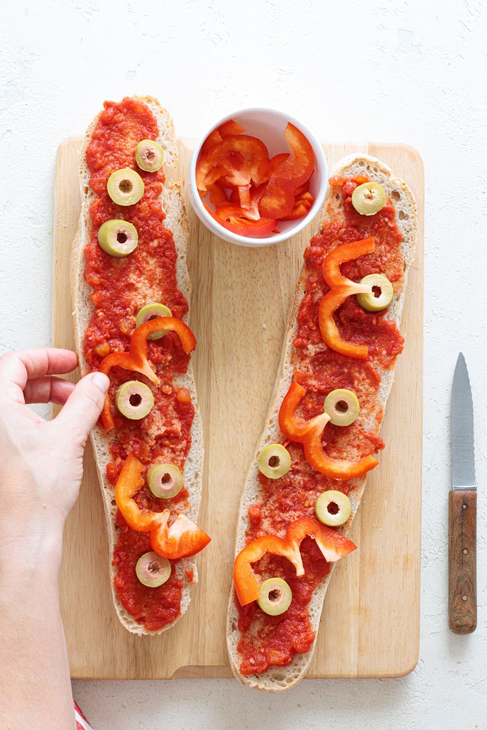 Thin slices of red bell pepper added on top of the olives and tomato sauce