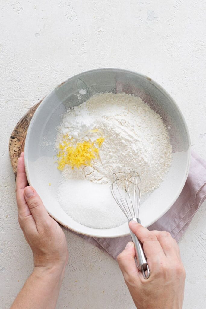 Mixing flour, sugar, baking powder, and lemon zest in a large bowl