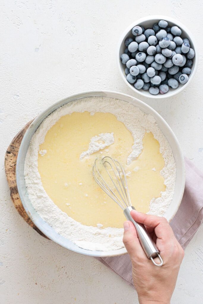 Combining wet and dry ingredients with a whisk in a mixing bowl
