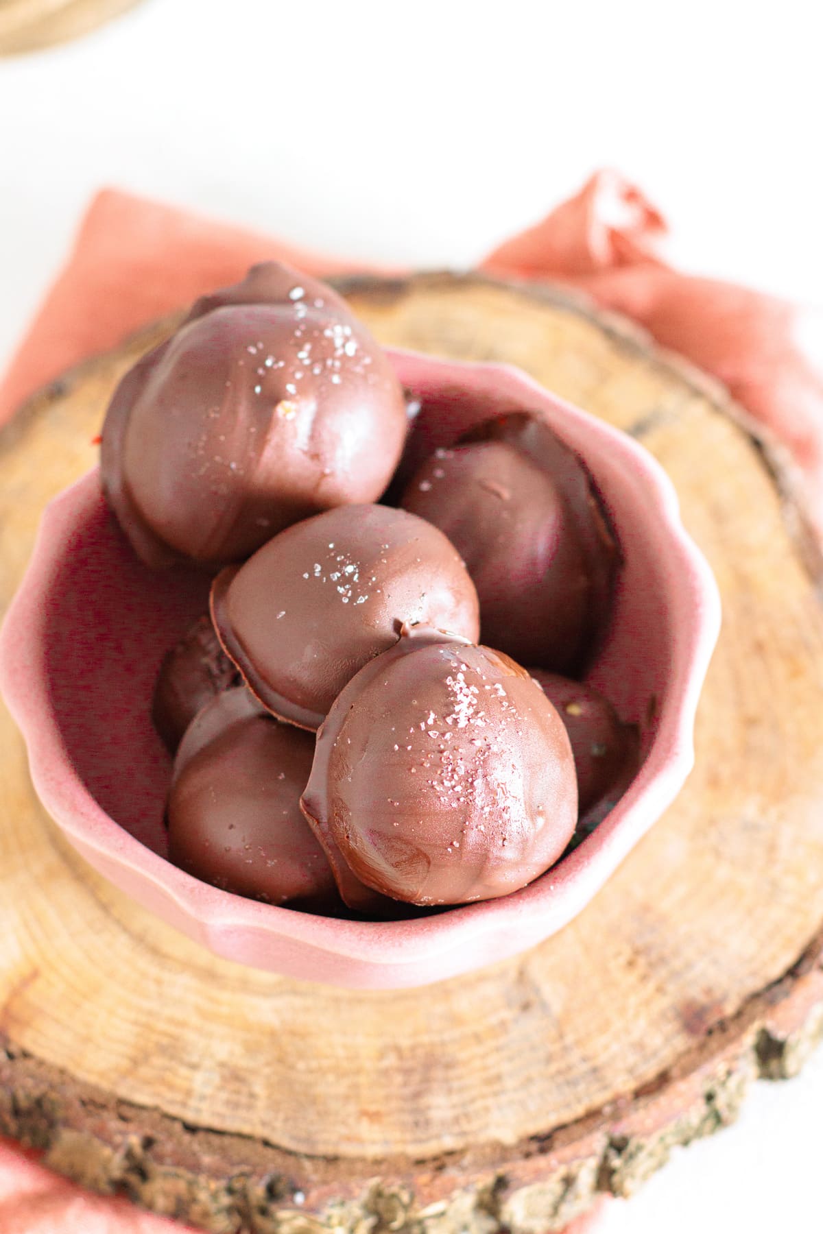 Smooth chocolate-dipped peanut butter balls with a simple sprinkle of sea salt for a refined finish.
