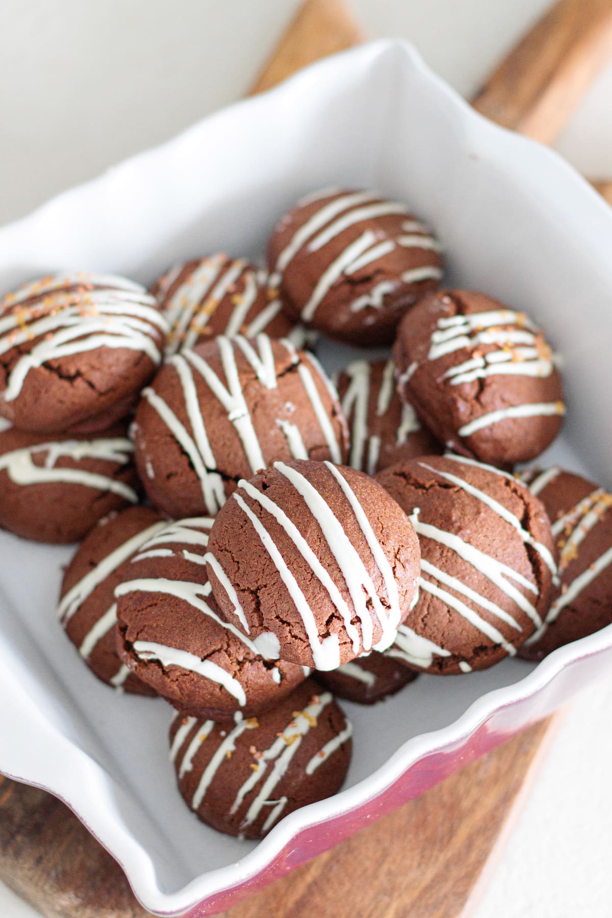 Chocolate bonbon cookies drizzled with white chocolate on a serving tray.