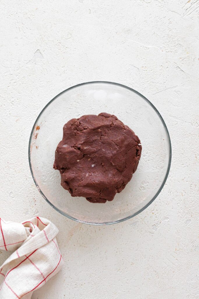 Chocolate cookie dough mixed and shaped into a ball in a glass bowl