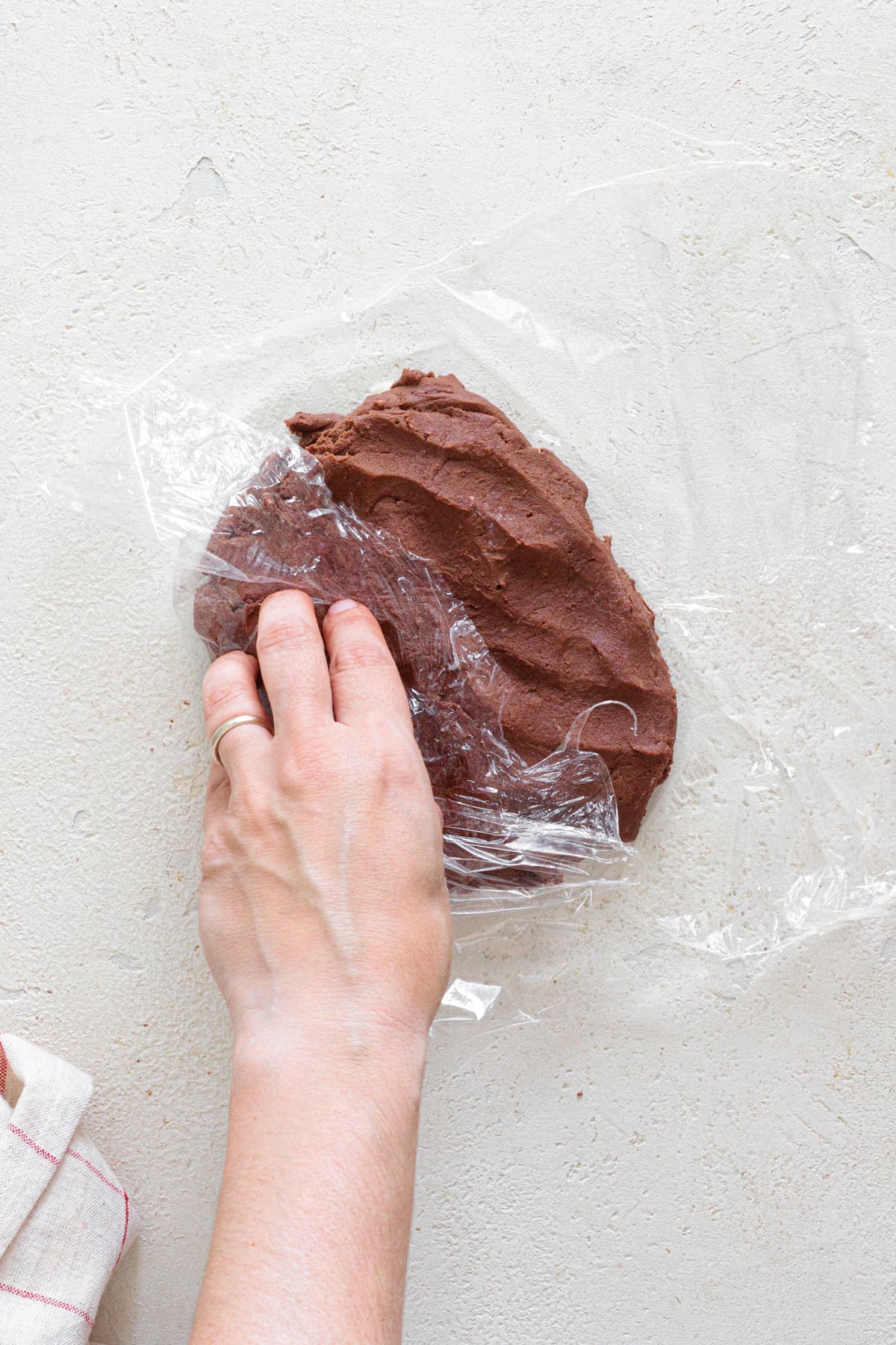Chocolate cookie dough being wrapped in plastic wrap before chilling.