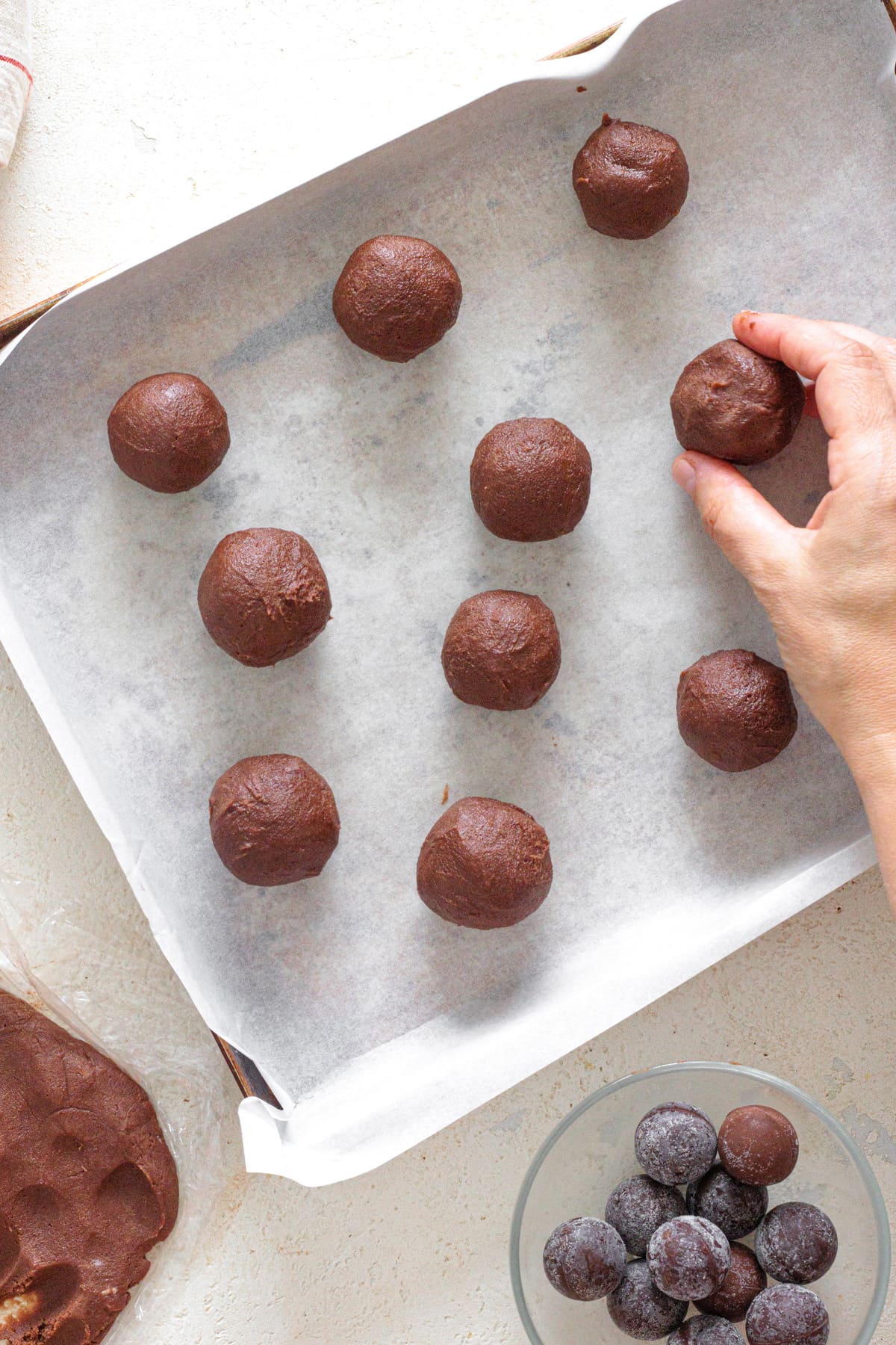 Chocolate cookie dough balls arranged on a baking sheet lined with parchment paper