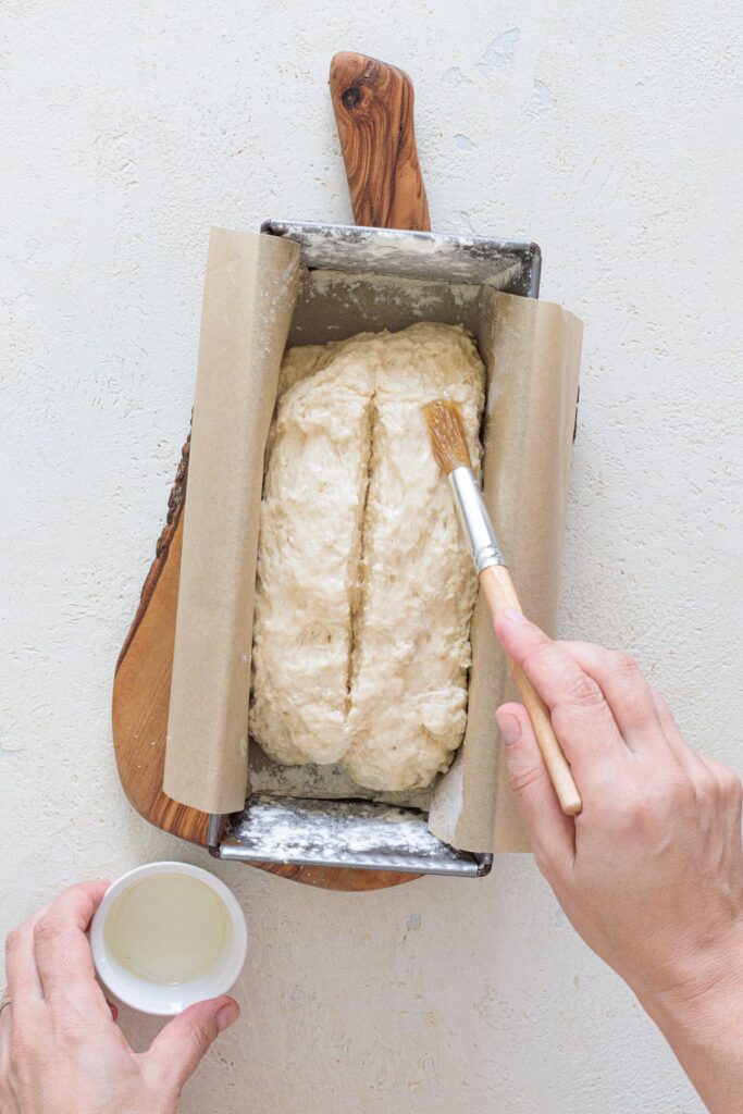 Brushing olive oil on bread dough before baking