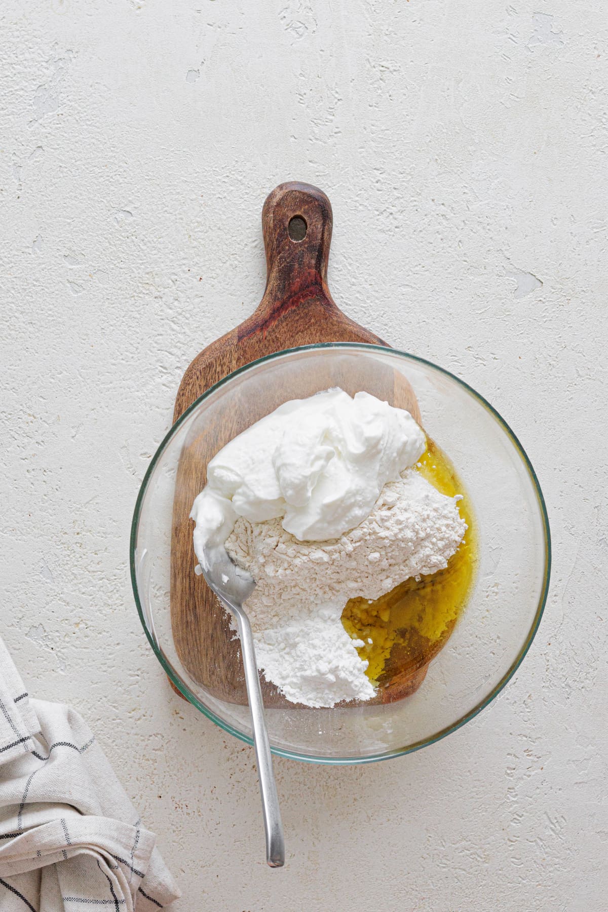 Greek yogurt, flour, baking powder, and olive oil combined in a mixing bowl for pizza dough.