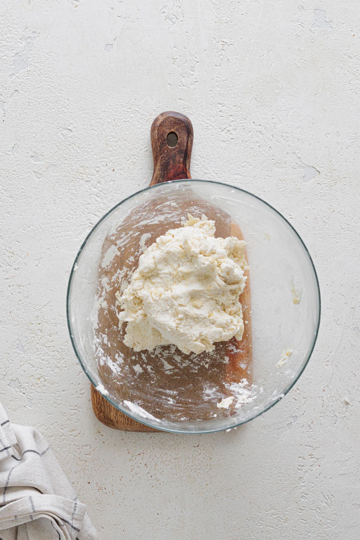 Ball of Greek yogurt pizza dough resting in a glass bowl after kneading.