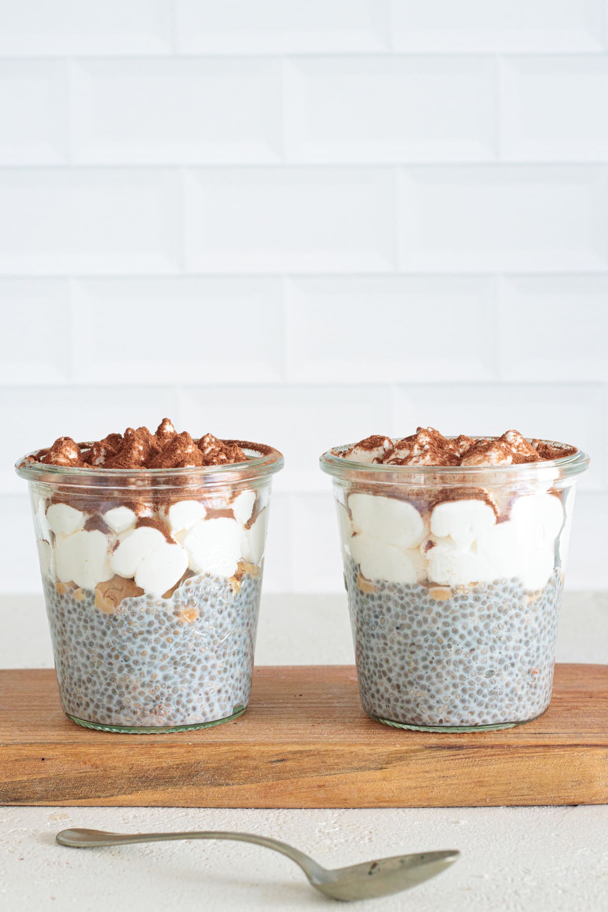 Two jars of tiramisu chia pudding with mascarpone cream and cocoa topping.