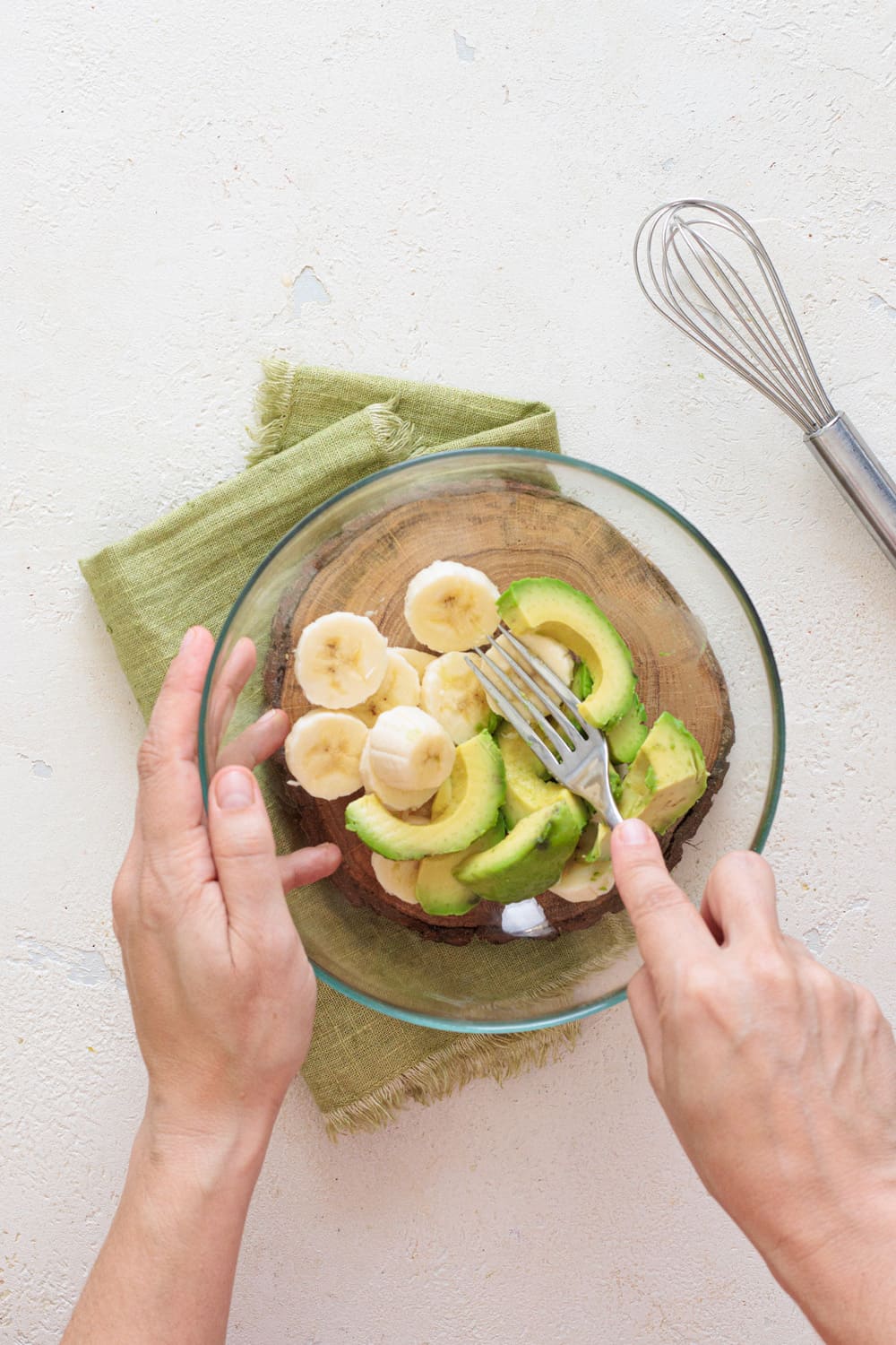 Mashing banana and avocado in a bowl with a fork