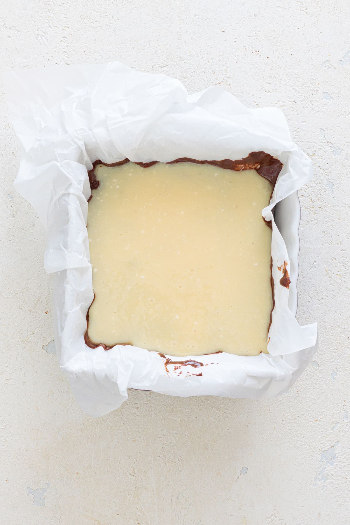 Pour the creamy vanilla layer over the chilled chocolate base.