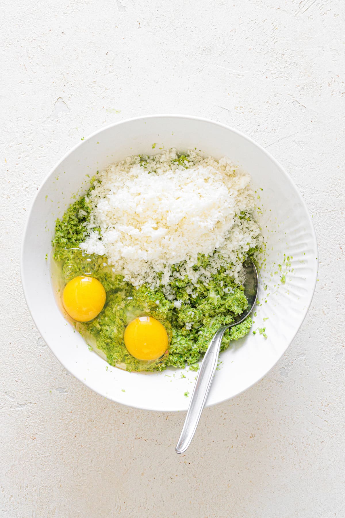 Bowl with broccoli, eggs, and grated Parmesan cheese ready to be mixed for the pizza crust