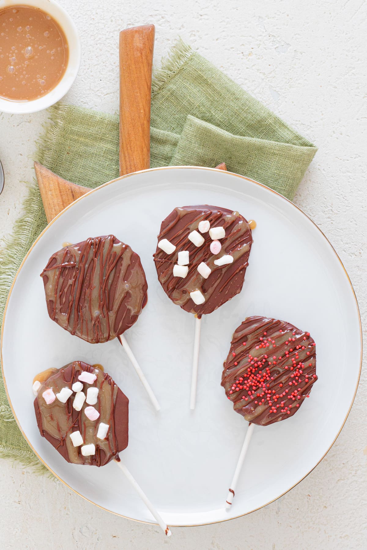 Chocolate-dipped Caramel Apple Slices with sprinkles and marshmallows.