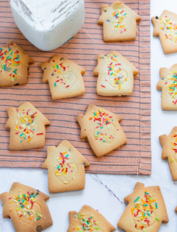 Golden Christmas sugar cookies decorated with colorful sprinkles.