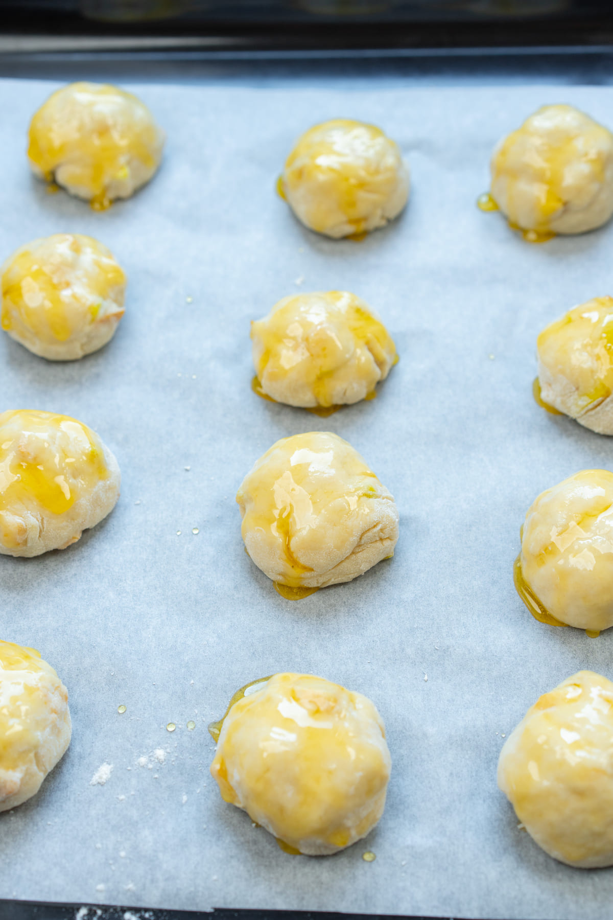 Unbaked apple dough balls on parchment-lined tray