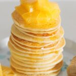 Fluffy Gluten-Free Buttermilk Pancakes topped with juicy orange slices and honey.