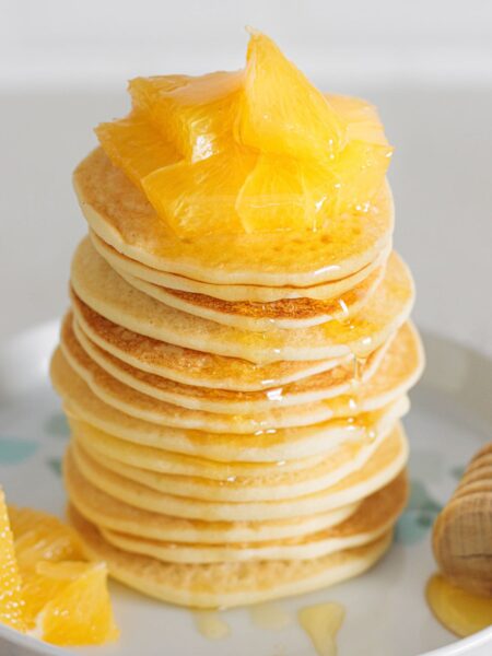 Fluffy Gluten-Free Buttermilk Pancakes topped with juicy orange slices and honey.