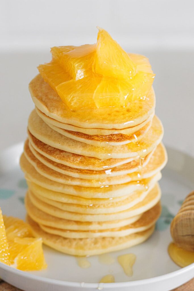 Fluffy Gluten-Free Buttermilk Pancakes topped with juicy orange slices and honey.