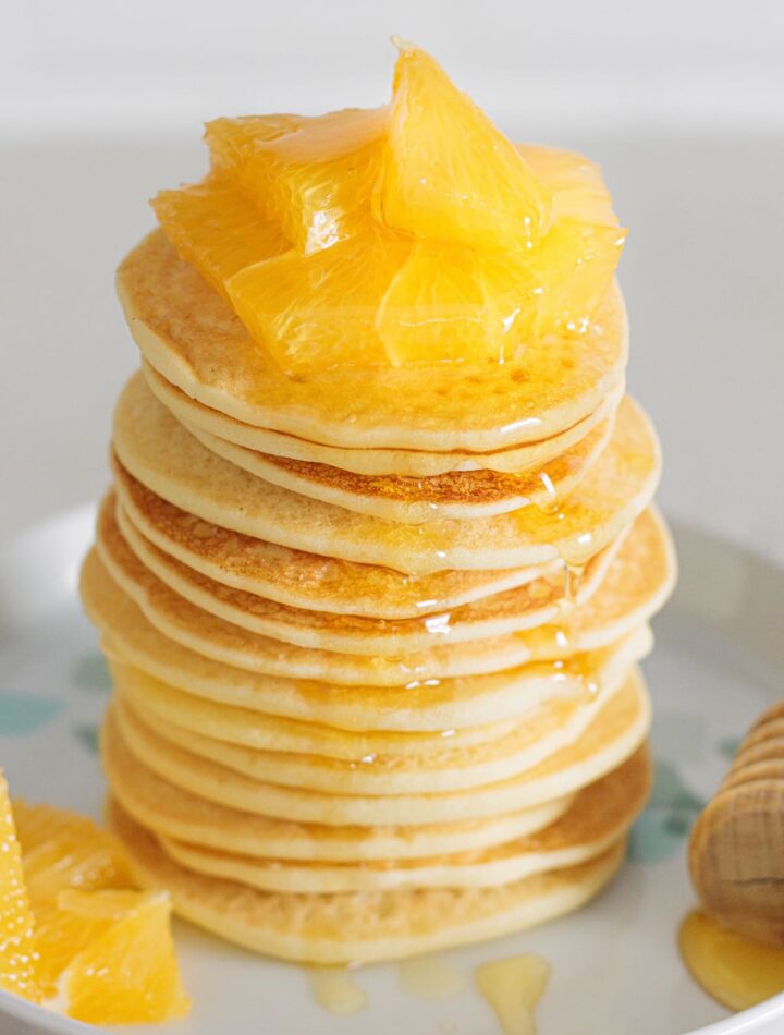 Fluffy Gluten-Free Buttermilk Pancakes topped with juicy orange slices and honey.