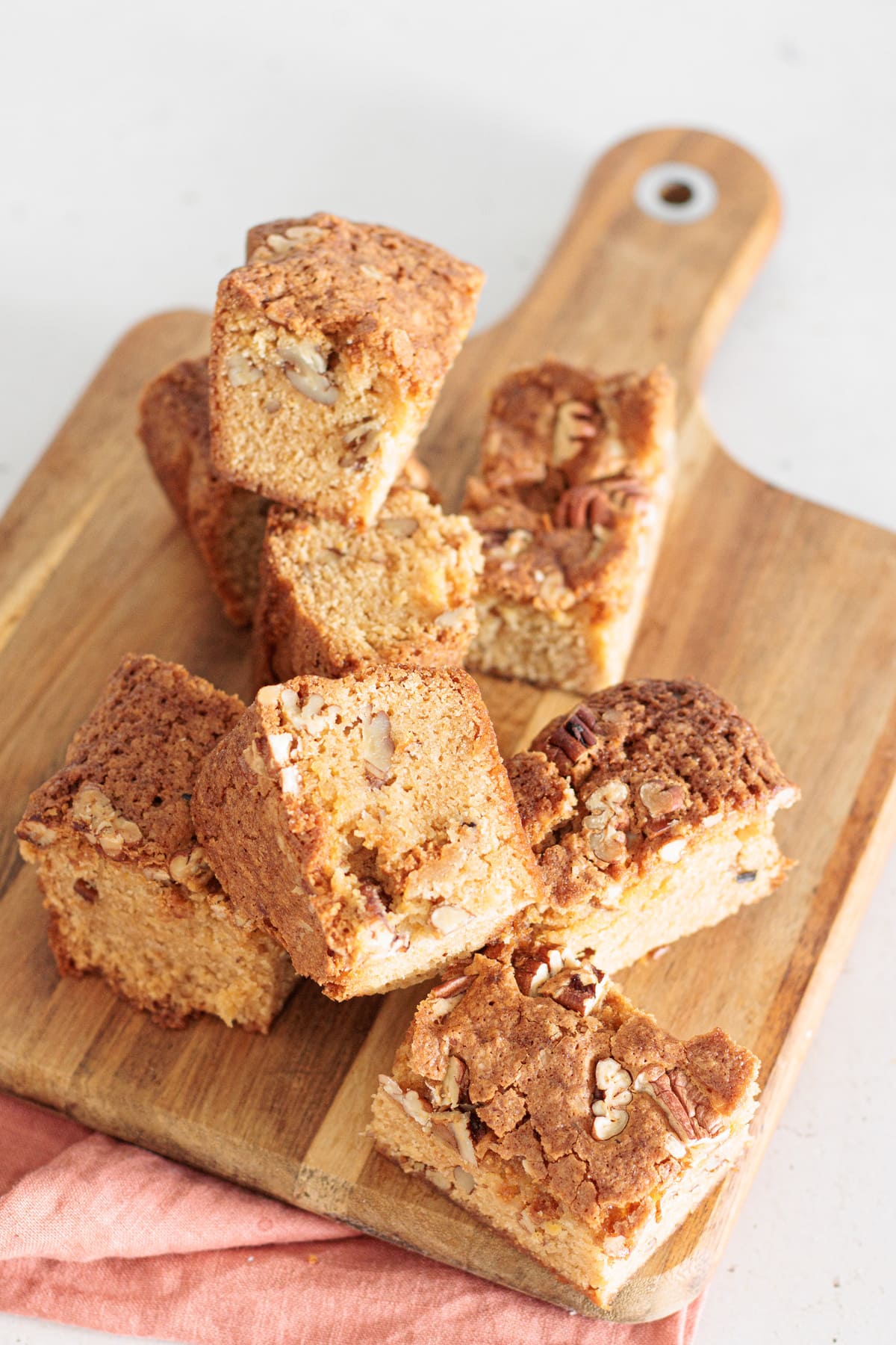 Maple pecan blondie squares stacked on a wooden board.