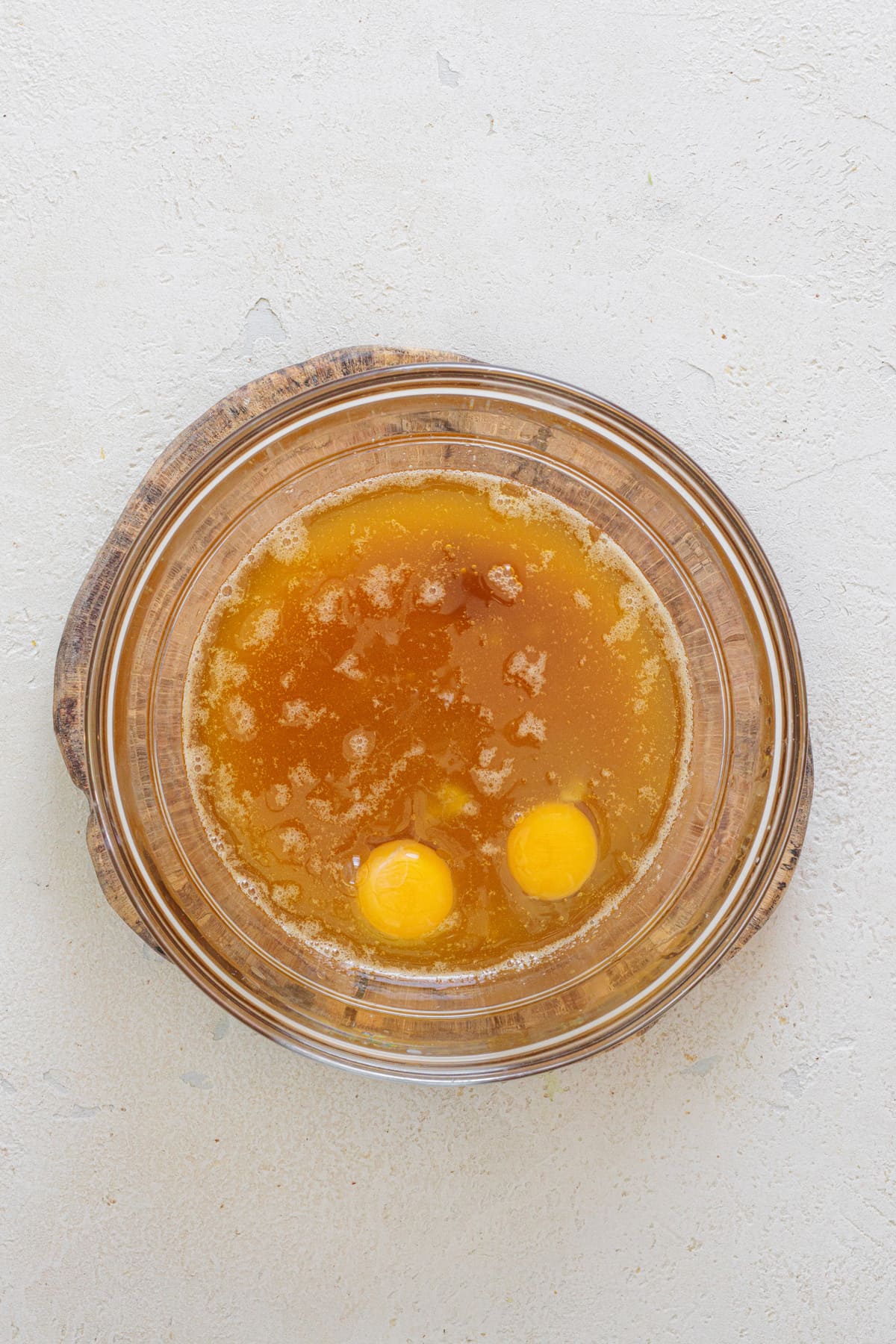 Two eggs added to a bowl of cooled brown butter mixture