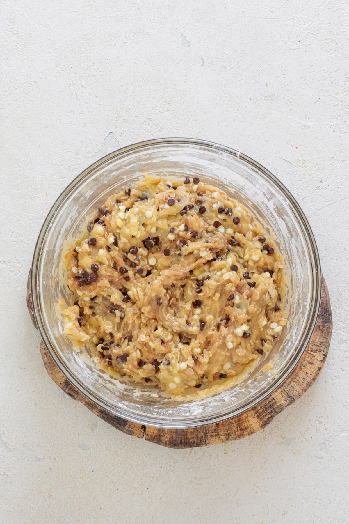 Cookie dough mixed with white and dark chocolate chips in a glass bowl