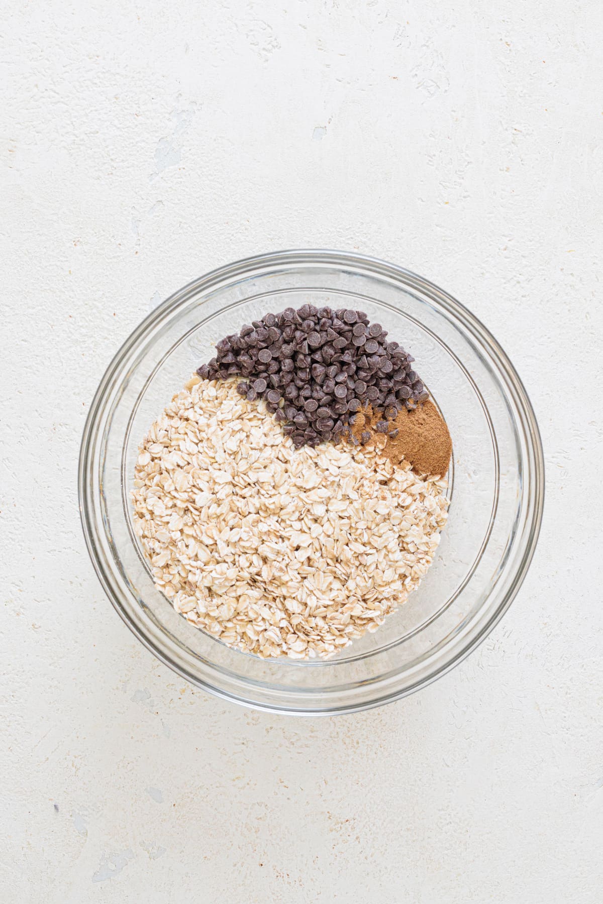Rolled oats, chocolate chips, and pumpkin spice in a glass bowl