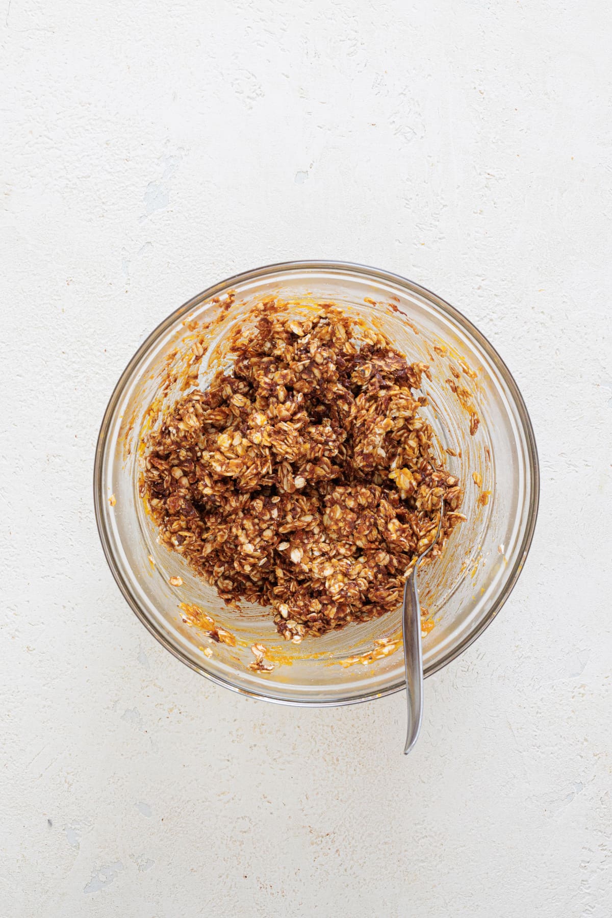Mixed pumpkin oat cookie dough in a glass bowl with a spoon
