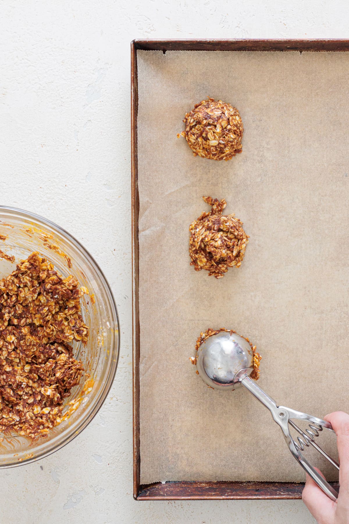 Scooping pumpkin cookie dough onto a parchment-lined baking sheet