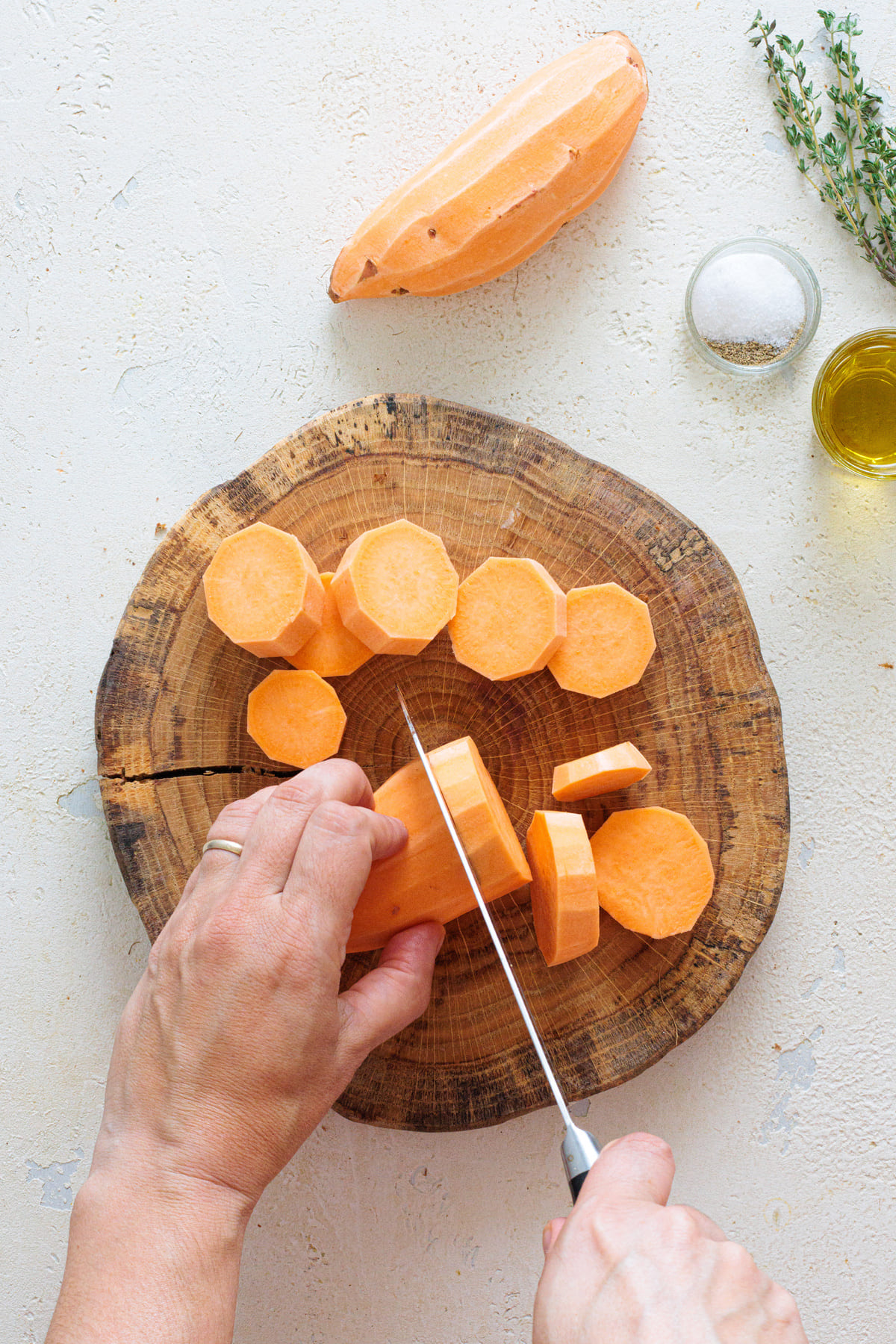 Cutting the sweet potatoes into thick, even rounds.
