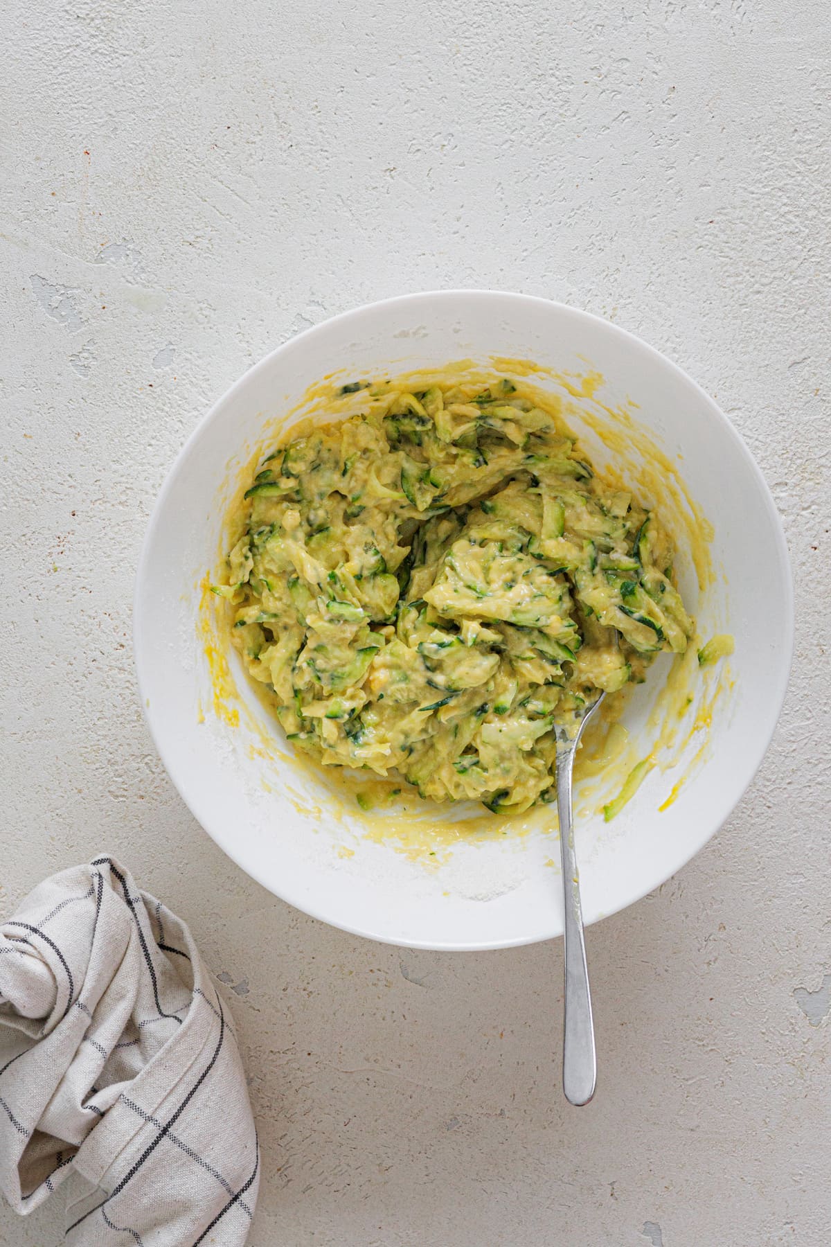 Bowl with zucchini, eggs, flour, and Parmesan mixed into batter