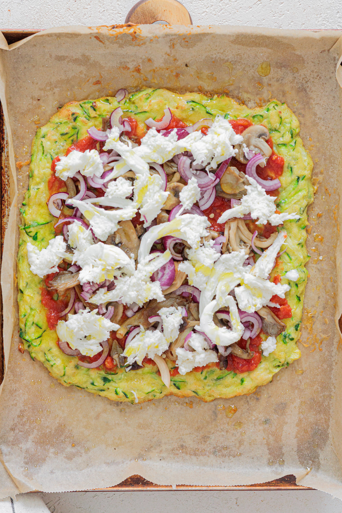 Zucchini crust pizza topped with tomato sauce, mushrooms, red onion, and mozzarella pieces