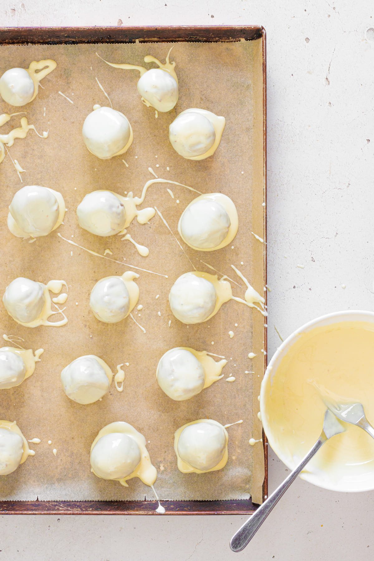 Tray of gingerbread truffles coated in melted white chocolate and left to set.