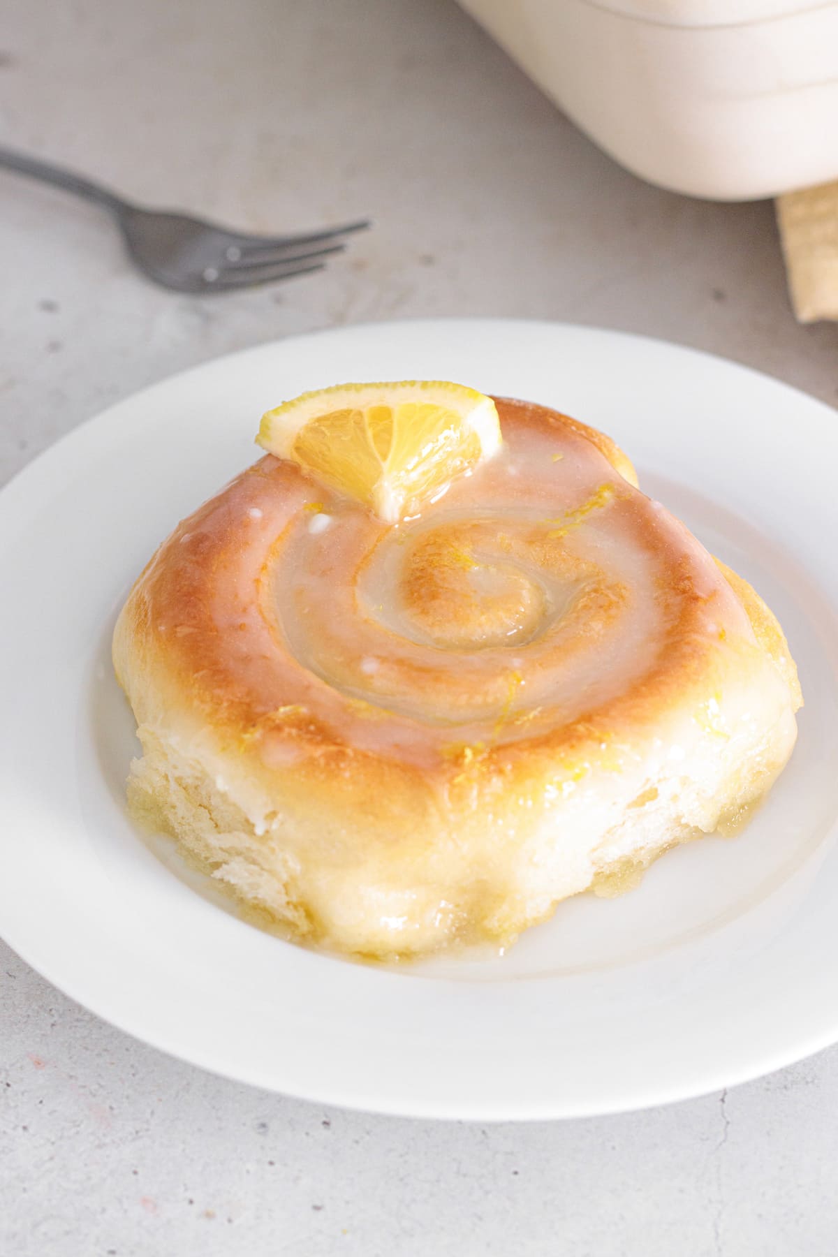 Plated soft Lemon Sweet Roll finished with a lemon slice.
