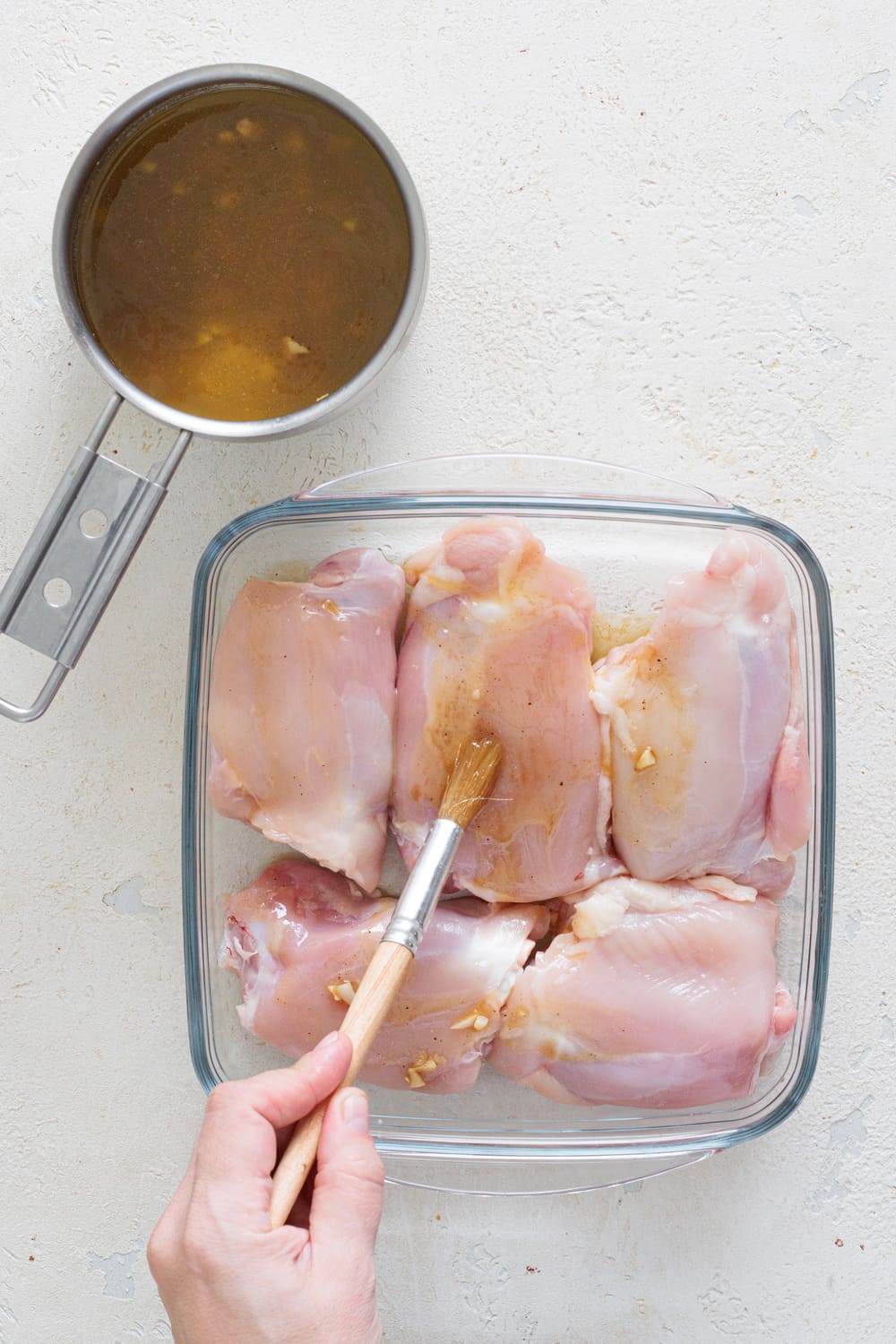 Generously brush the chicken thighs, skin side up, with part of the butter sauce.
