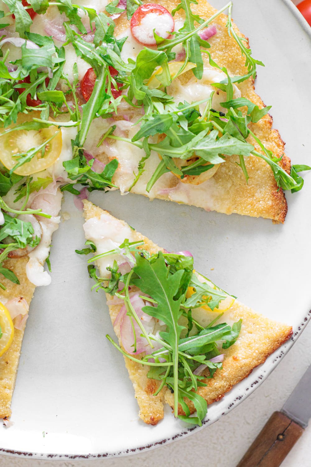 Cauliflower Pizza Crust with mozzarella, tomatoes, onions, and fresh arugula