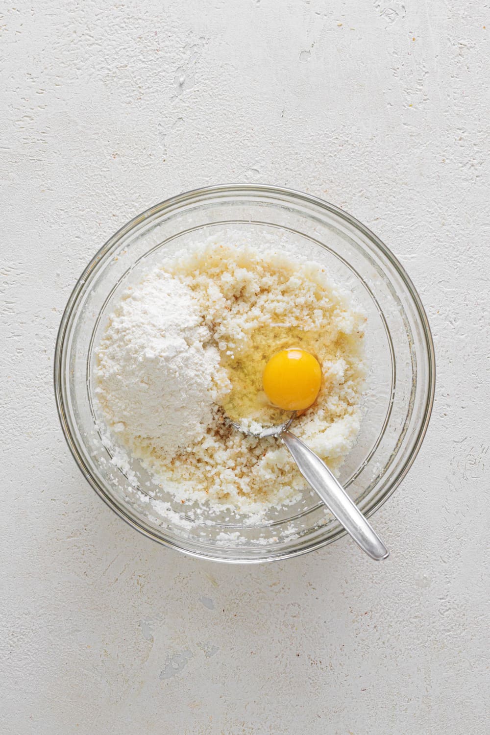 After removing the excess moisture and cooking your cauliflower for about 5 minutes, transfer it to a bowl and add the egg, flour, and condiments.
