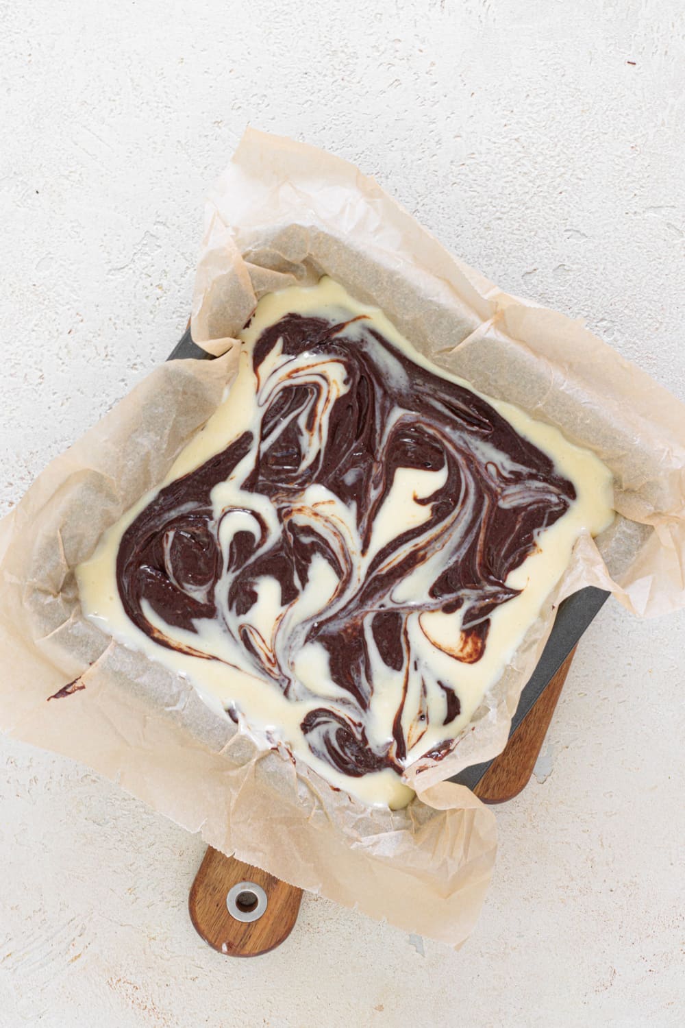 Drop spoonfuls of the reserved brownie batter over the top and, using a knife, gently swirl both layers together.