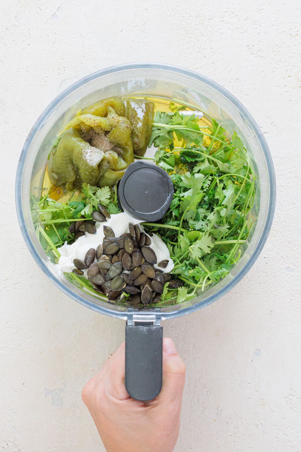Add the peeled pepper, the cilantro, pumpkin seeds, garlic, yogurt, vinegar, salt, pepper, and olive oil into the blender.
