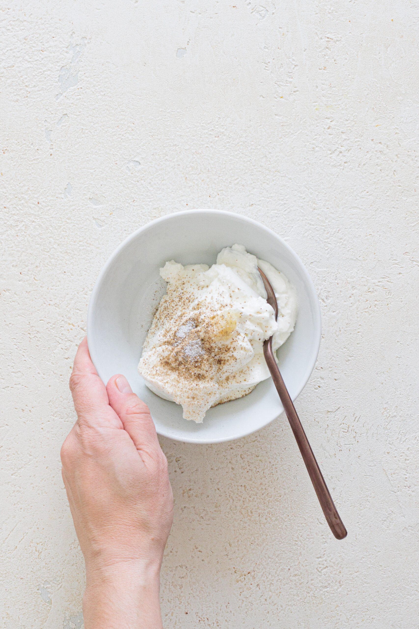 Add greek yogurt, grated garlic, salt, and pepper to a bowl.