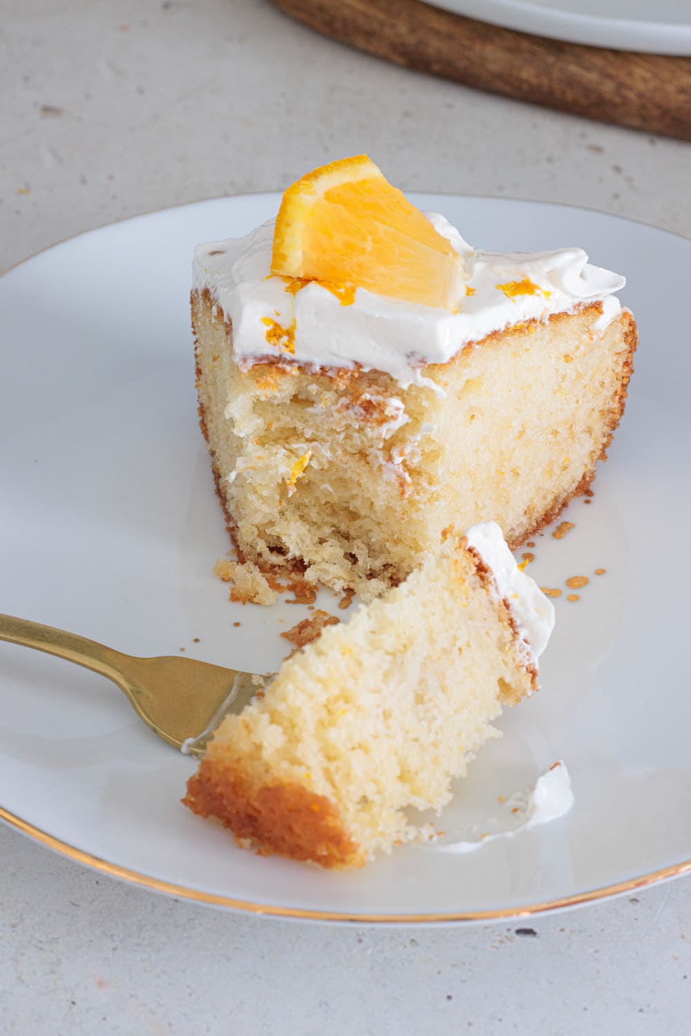 Slice of soft orange creasicle cake soaked in syrup and topped with whipped cream